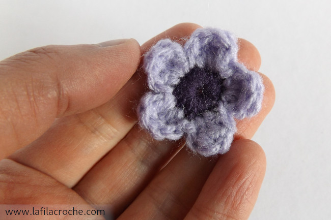 Fleur violette au crochet dans une main
