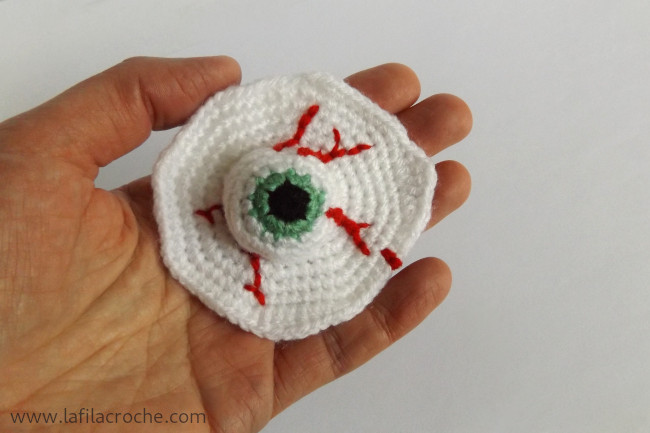 Un oeil vert sur le plat crocheté, présenté dans ma main
