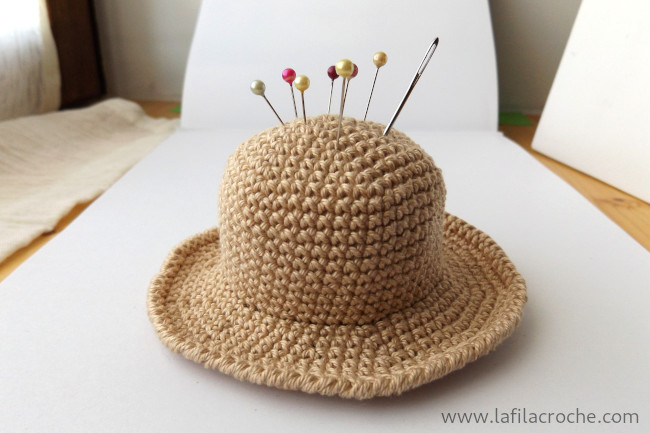 Le pique-épingles chapeau au crochet avec quelques épingles de couture piquées dedans, il n’a pas encore de ruban pour l’enjoliver.
