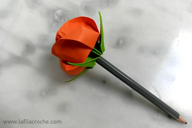 La même rose enfilée sur le bout d’un crayon de mine