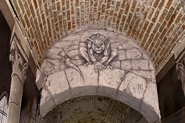 Un trompe l’œil représentant une sorte de gargouille, peint sur une arche dans un passage couvert de Laon
